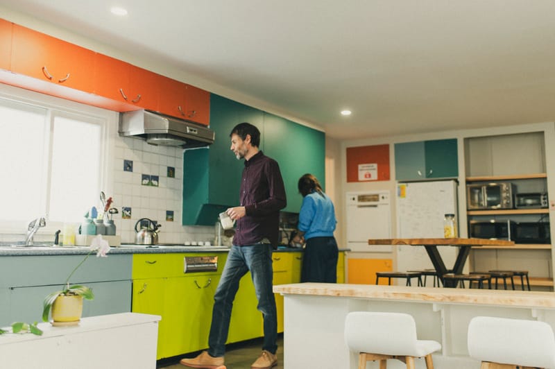 Cuisine commune de l'Espace Ko — couple devant la cafetière, ambiance conviviale