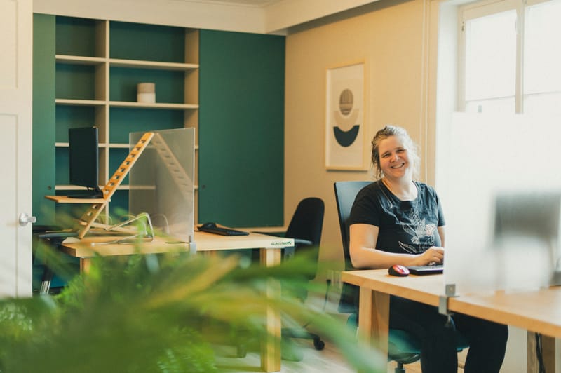 Femme souriante à un poste avec la bibliothèque sarcelle en arrière-plan
